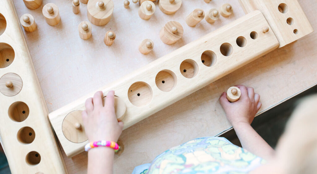 Sunny Hollow Montessori Events, student working with the Knobbed Cylinders