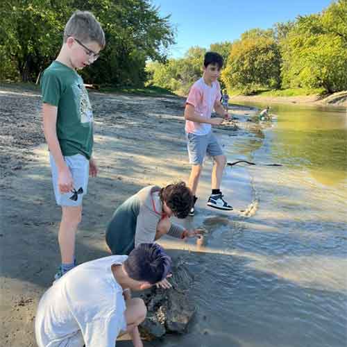 Group of boys playing in the water along a river.