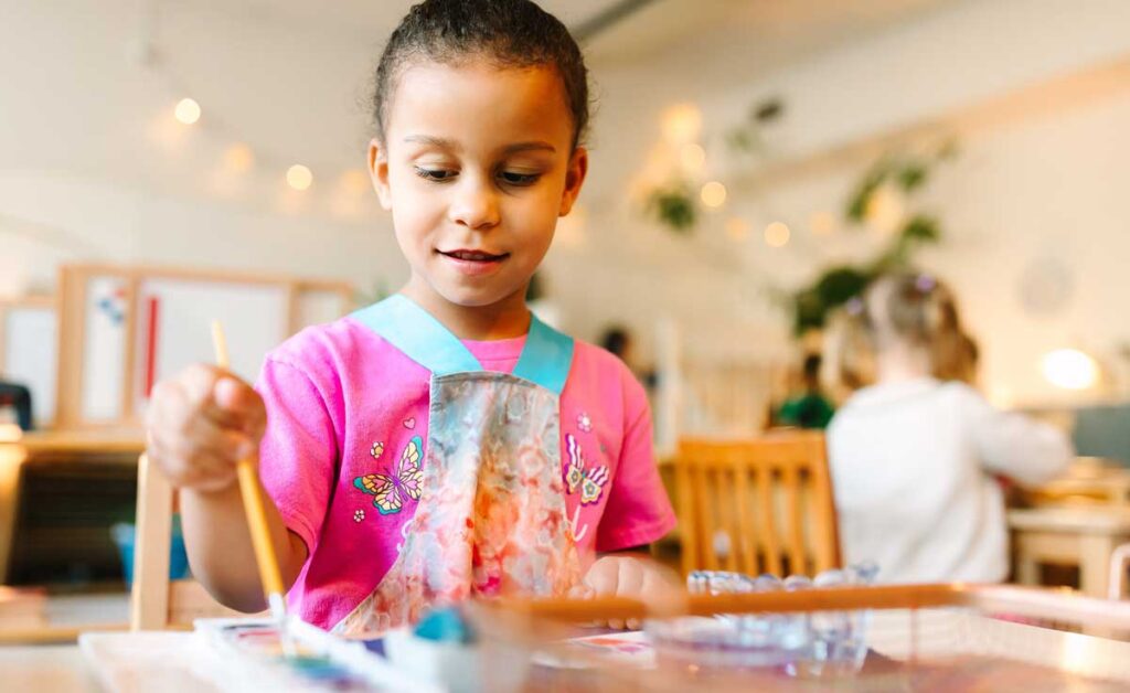 Close up of young girl painting at table.