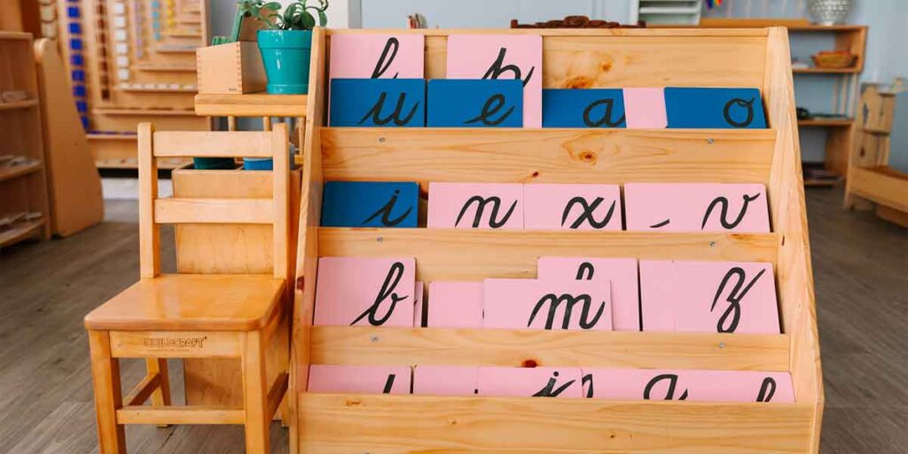 A wooden shelf holding examples of cursive letters.
